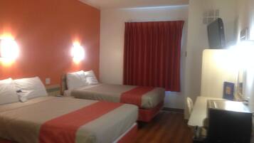 Habitación de hotel con dos camas, un escritorio y una televisión.