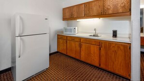 A compact kitchen with a refrigerator, microwave, sink, and wooden cabinets. - Super 8 by Wyndham Goodland (Goodland)