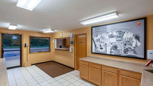 A hotel lobby with a tiled floor, wooden cabinets, a reception area with a framed photo, and a door leading outside. - Super 8 by Wyndham Goodland (Goodland)