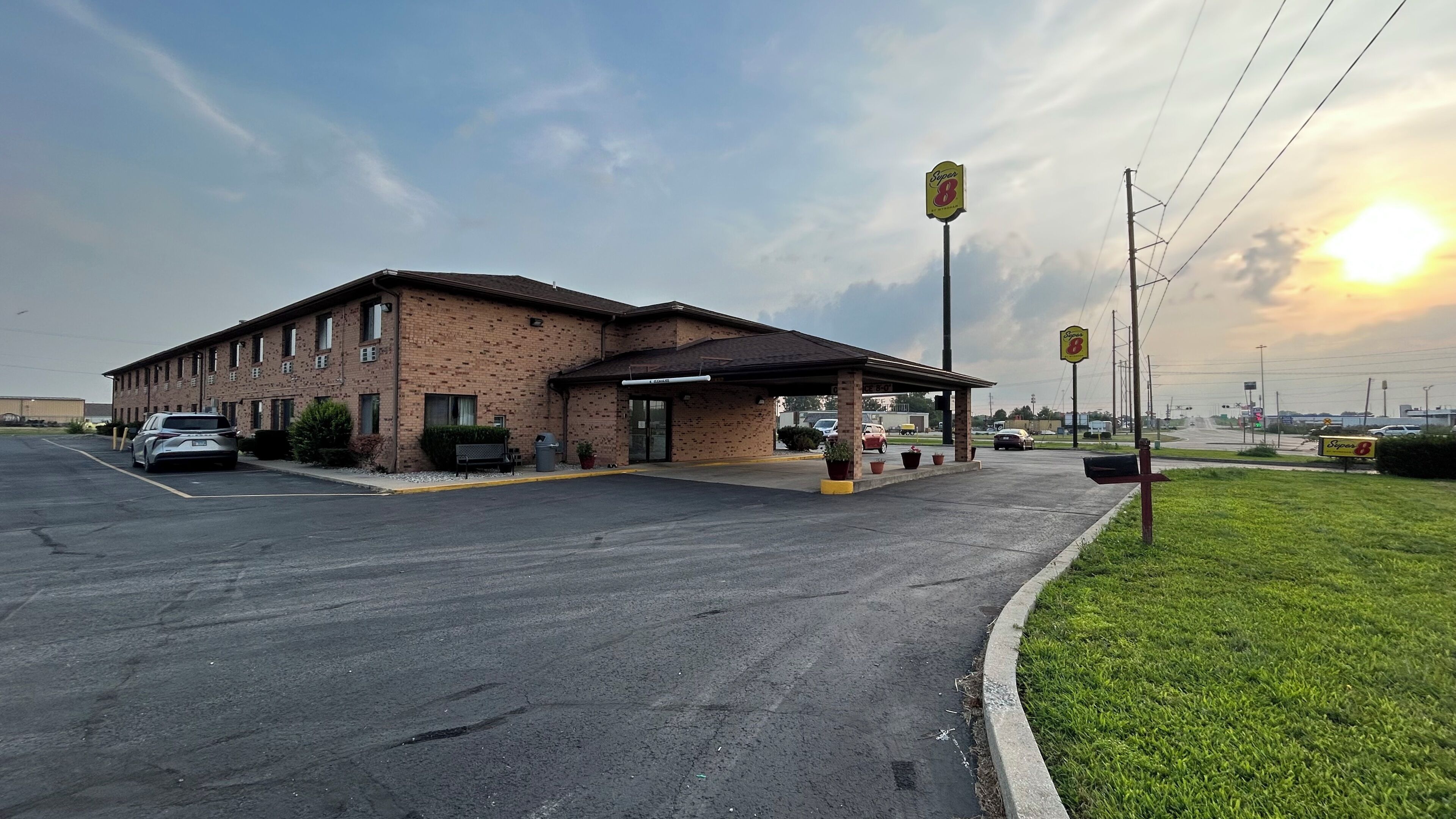 A motel with a brick exterior, a covered parking area, and a gas station sign.