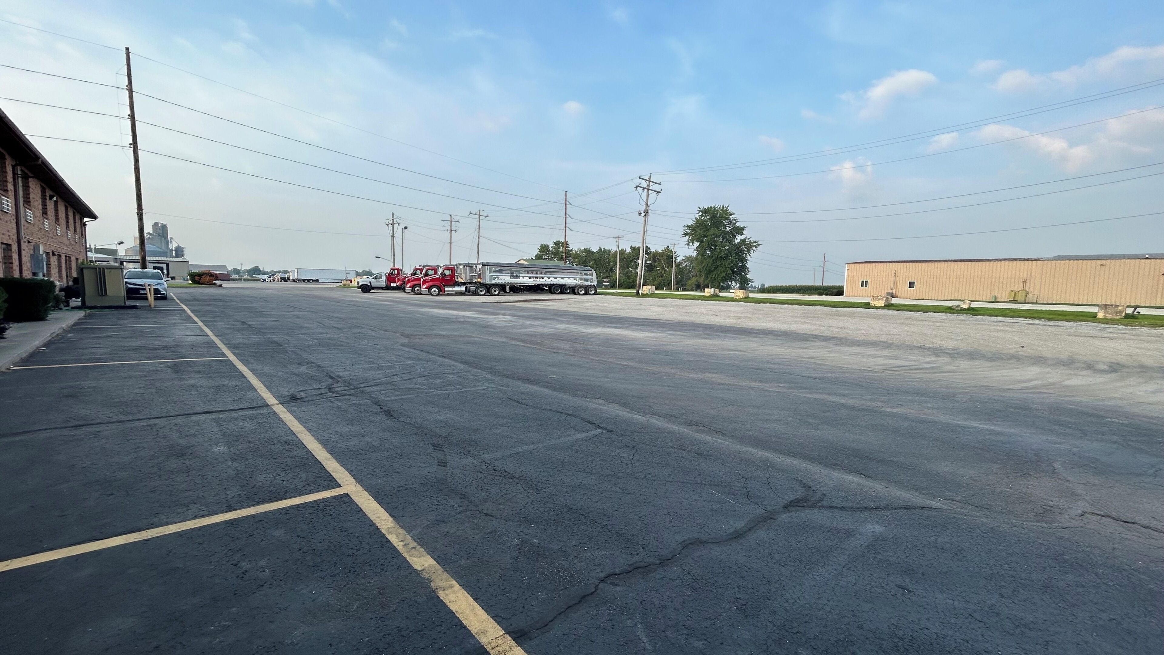 A parking lot with a fire truck and a trailer. There are buildings and power lines in the background.