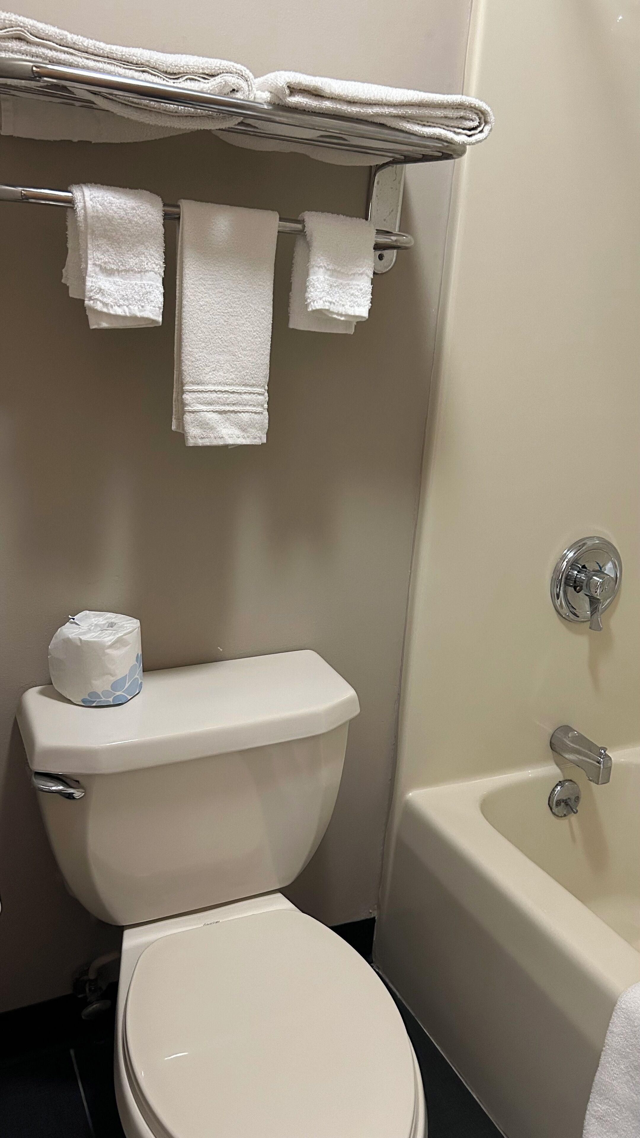 Un baño con inodoro, bañera y toallero con varias toallas.
