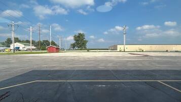 An empty parking lot with a red building and a large warehouse.