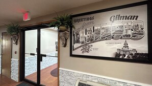 A hallway with a framed welcome sign for Gilman, featuring a cityscape and the state capitol building. - Super 8 by Wyndham Gilman (Gilman)