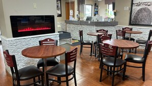 A restaurant with a stone wall, a fireplace, and several wooden tables and chairs. - Super 8 by Wyndham Gilman (Gilman)