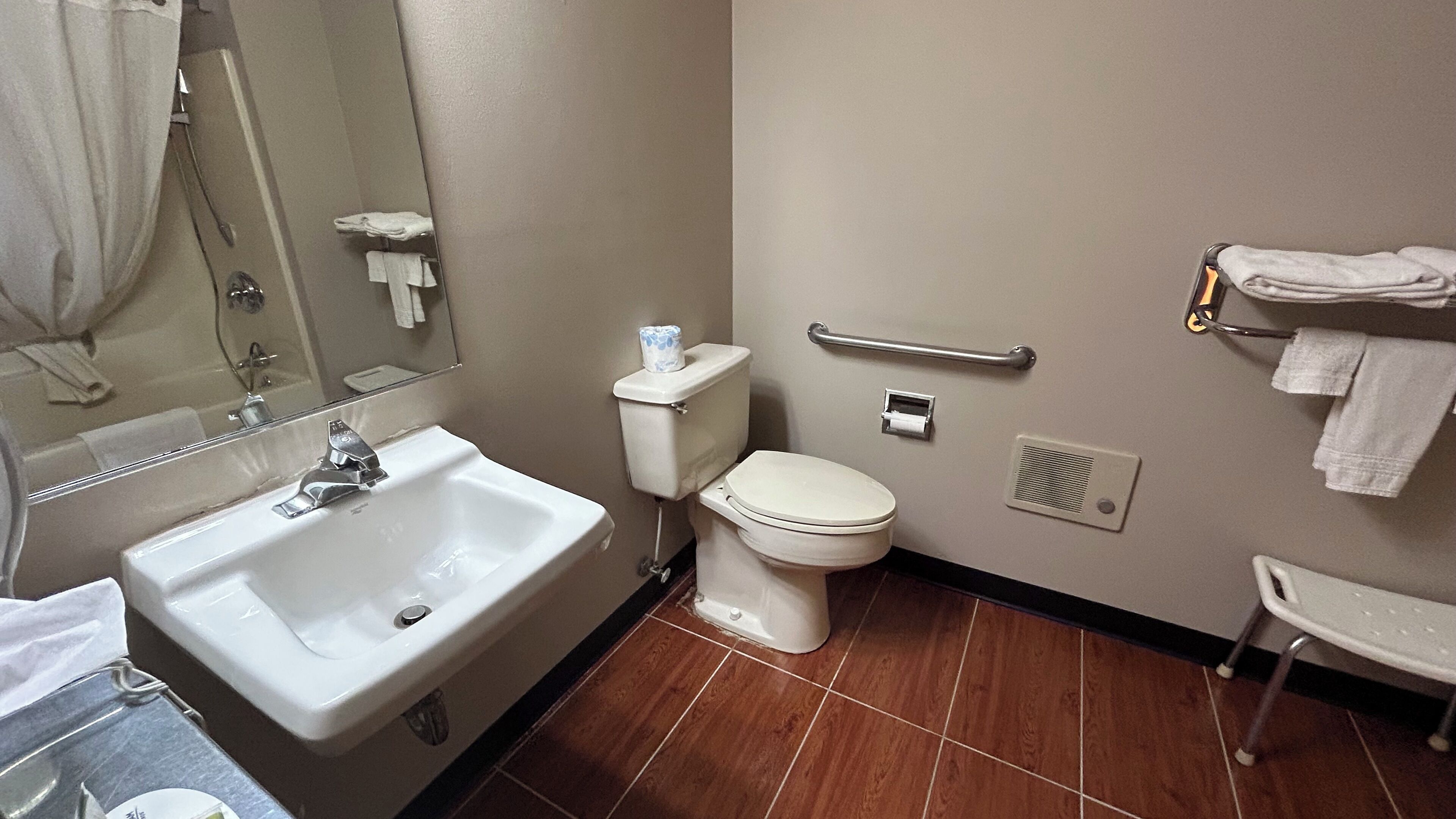 A bathroom with a sink, toilet, and handrail.