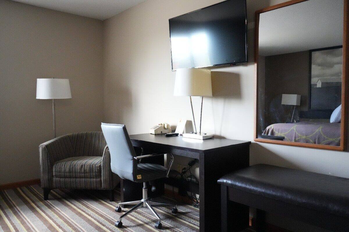 Habitación de hotel con escritorio, silla y una cama grande.