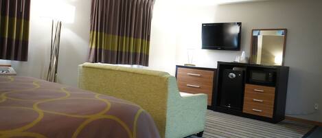 A hotel room with a bed, a desk, a television, a safe, and a mirror.