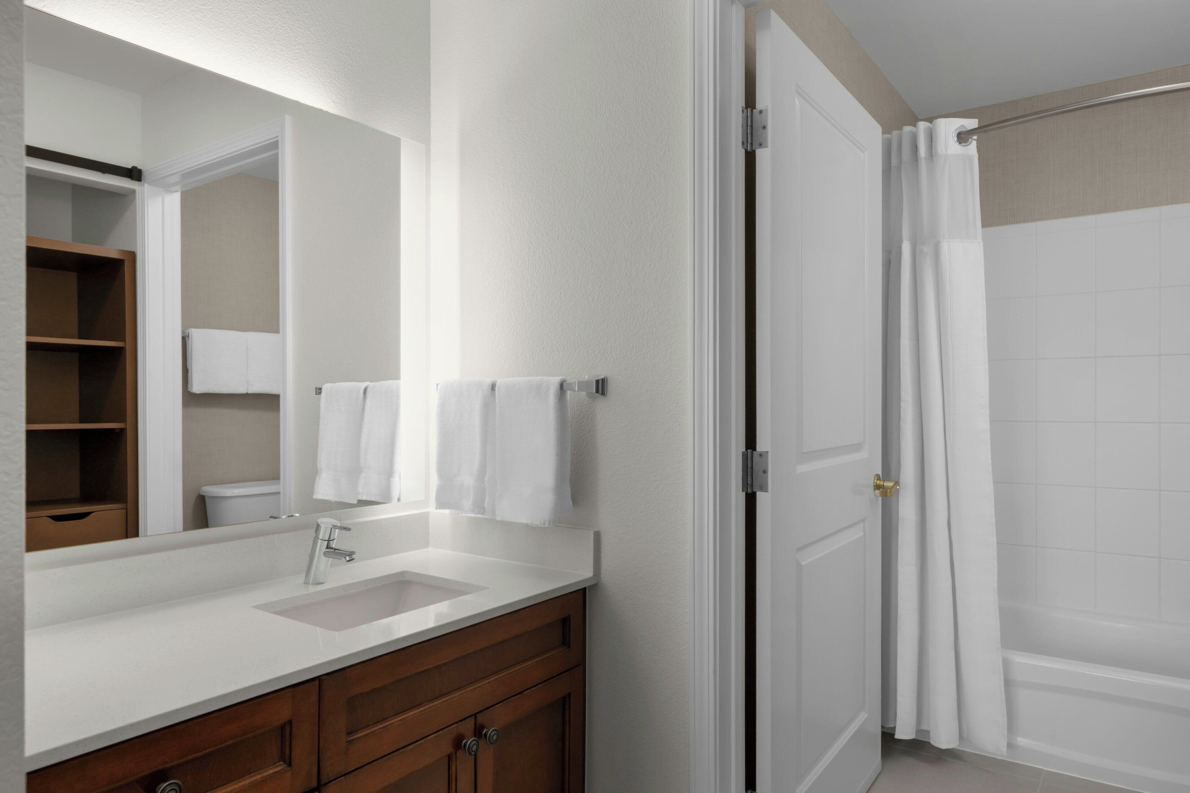 A bathroom with a white sink, wooden vanity, a mirror, and a shower curtain.