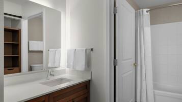 A bathroom with a white sink, wooden vanity, a mirror, and a shower curtain.