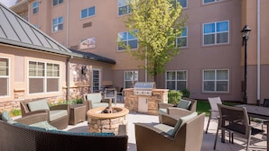 An outdoor patio area with wicker furniture, a stone fire pit, and a grill. - Residence Inn by Marriott Boise West (Boise)