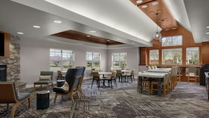 A spacious room with a fireplace, multiple seating areas, large windows, and a patterned carpet. - Residence Inn by Marriott Boise West (Boise)