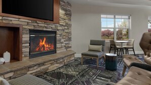 A stone fireplace with a fire, a television mounted above it, and a seating area with chairs and a table. - Residence Inn by Marriott Boise West (Boise)