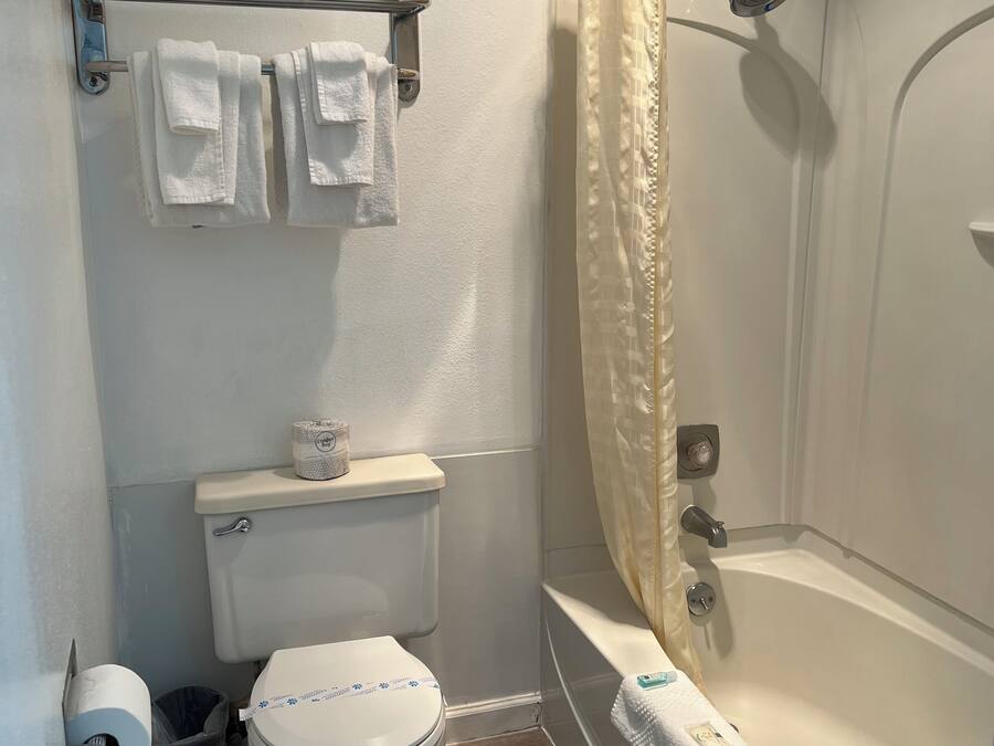 Un baño pequeño con inodoro, ducha con cortina y un perchero con toallas.