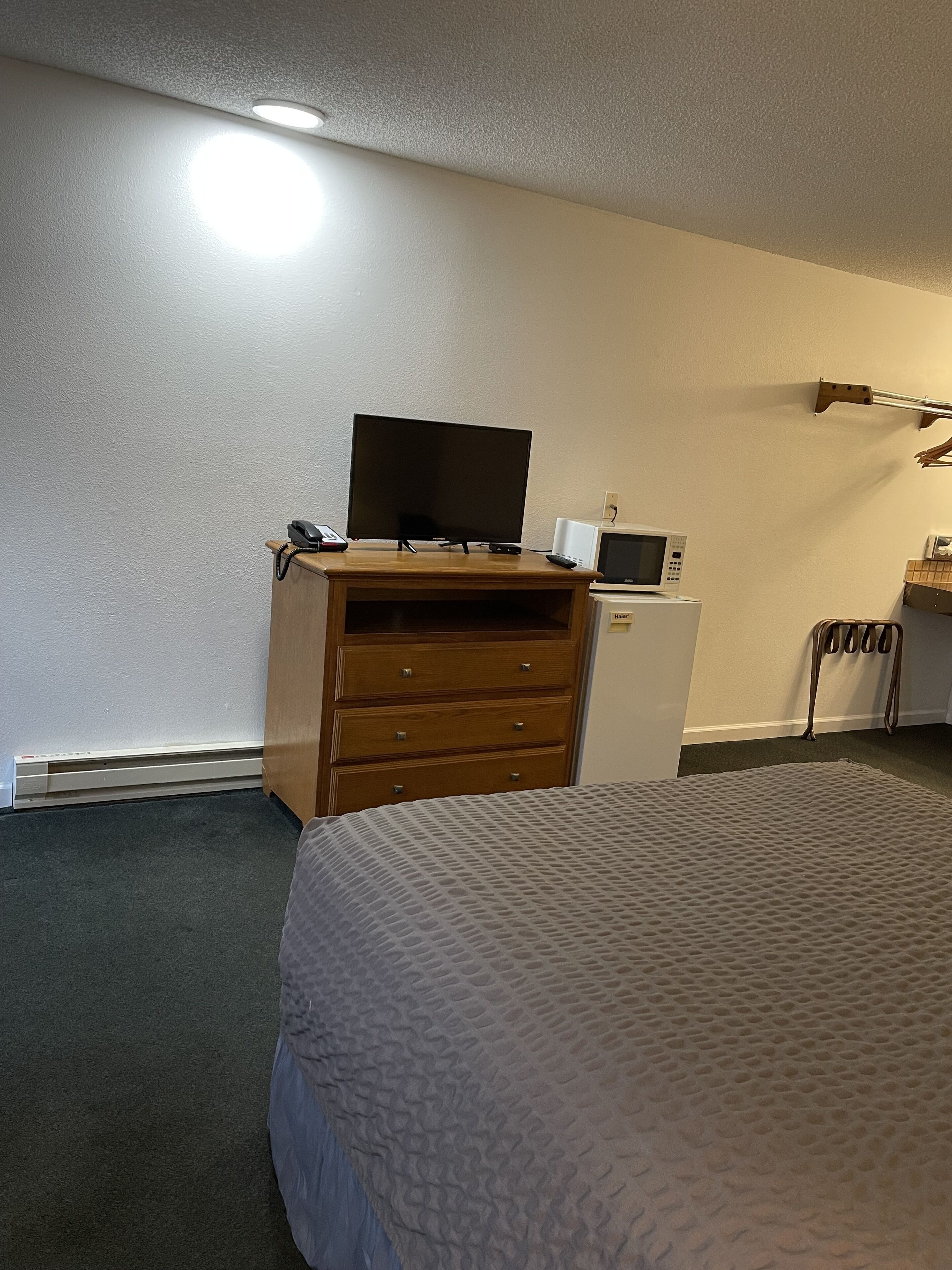 Une chambre d’hôtel équipée d’un lit, d’une commode, d’une télévision, d’un four à micro-ondes et d’un radiateur.