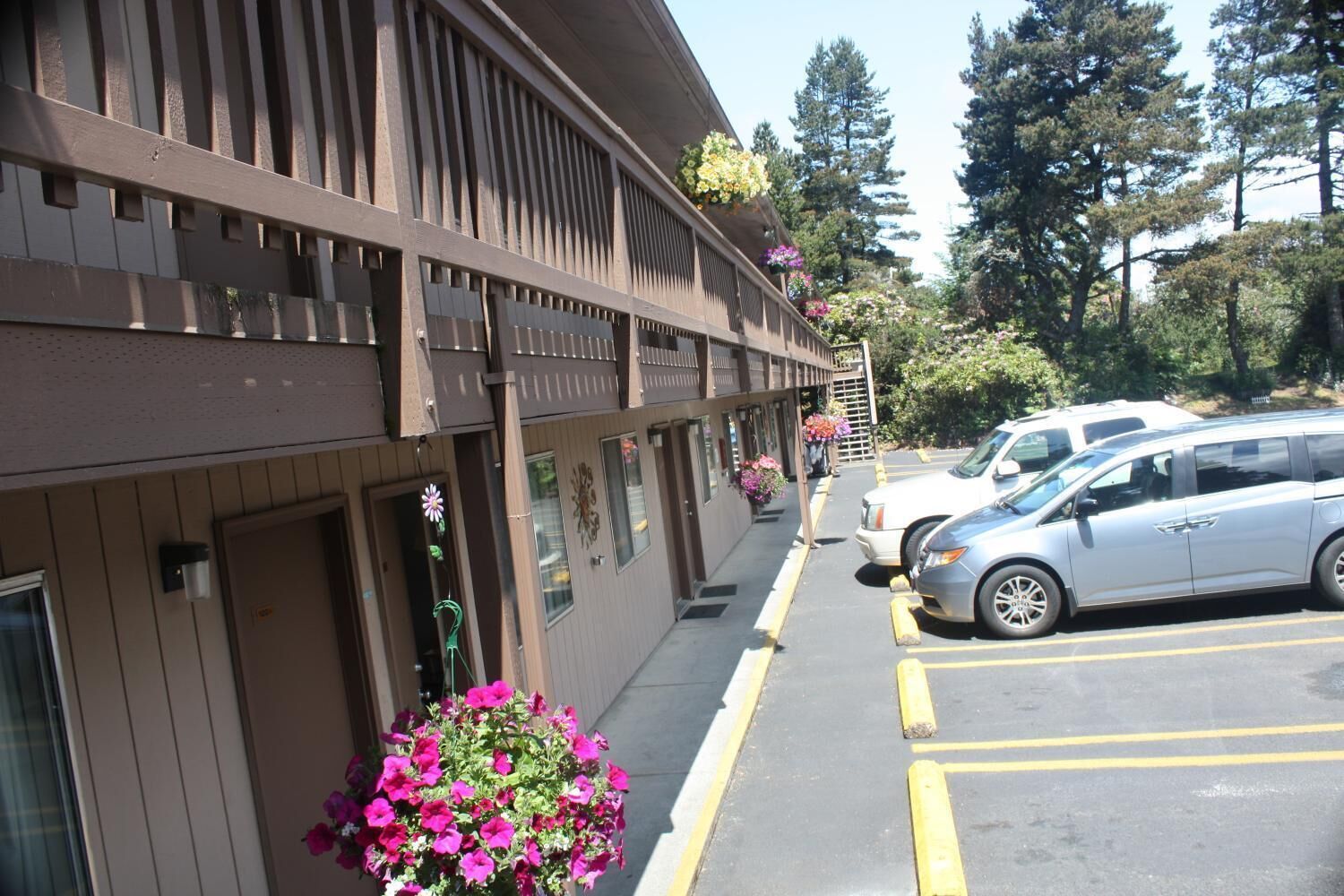 A building with a parking lot, a vehicle, and a flower planter.