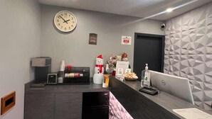 Un espace d’accueil moderne, doté d’un bureau, d’un ordinateur et d’une horloge murale.