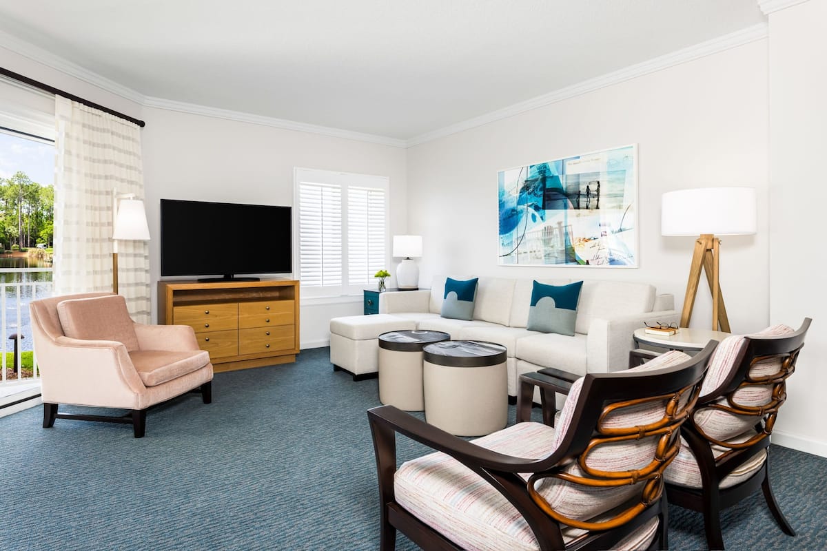 A modern living room with a sofa, armchairs, a coffee table, and a flat-screen TV.