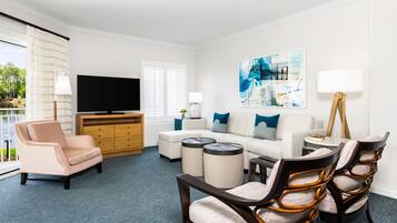 A modern living room with a sofa, armchairs, a coffee table, and a flat-screen TV.
