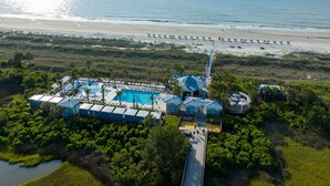 Oversigtsbillede af et resort med swimmingpool, strandparasoller og en strand.