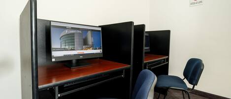 A computer desk with a monitor displaying a webpage, a chair, and a no-smoking sign on the wall.