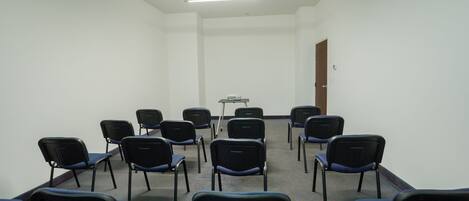 A conference room with rows of chairs, a projector, and a whiteboard.