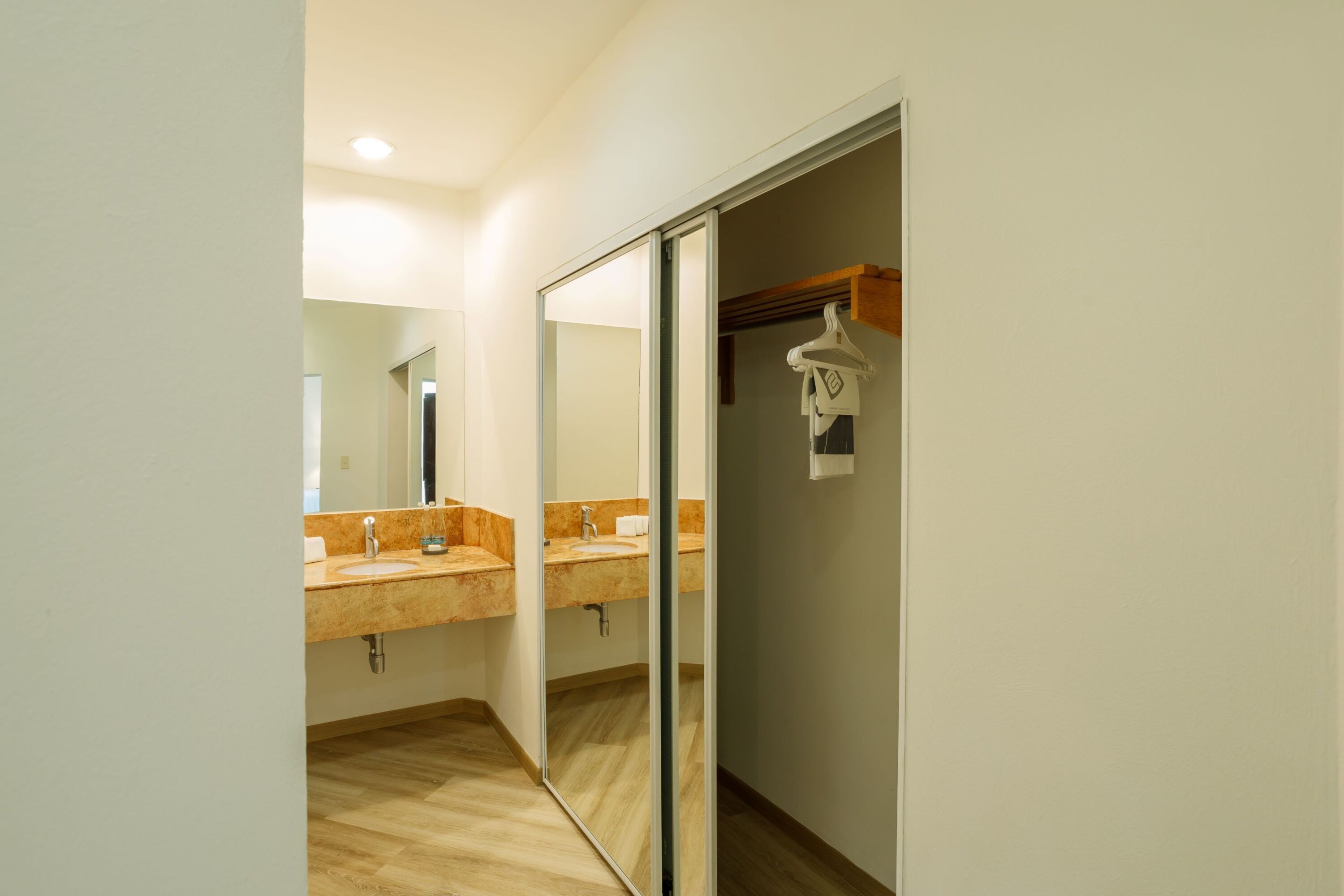 A modern bathroom with two sinks, a mirror, and a walk-in closet.
