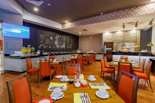 A restaurant with wooden tables and orange chairs, a blackboard menu, and a bar area. - Camino Real Pachuca (Pachuca)