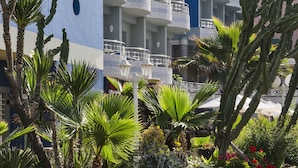 A hotel with multiple balconies, palm trees, and a well-maintained garden. - Club Val D Anfa (Casablanca)