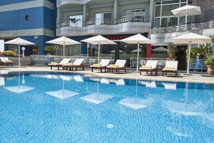 Una piscina al aire libre, sombrillas, sillones reclinables de piscina