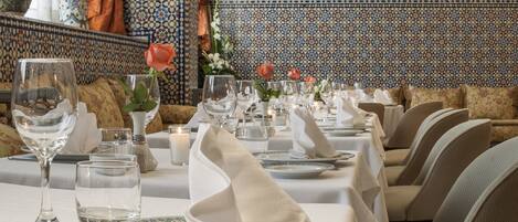 A dining area with tables set for a meal, featuring a patterned tile wall and decorative vases.