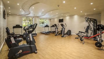 Un gimnasio con cintas de correr, elípticas y equipo de levantamiento de pesas.