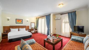 Una habitación de hotel con una cama grande, un sofá, un televisor y un escritorio con lámpara.