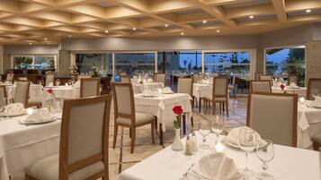 A restaurant with multiple tables set for dining, featuring white tablecloths, chairs, and candles.