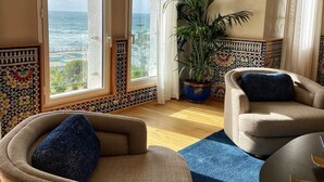 A room with a view of the ocean, two armchairs, a potted plant, and a tiled wall with a geometric pattern. - Club Val D Anfa (Casablanca)