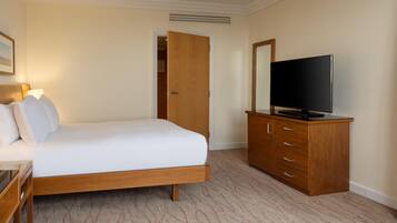 Una habitación de hotel con una cama, un televisor sobre un mueble de madera y una puerta que da a otra habitación.