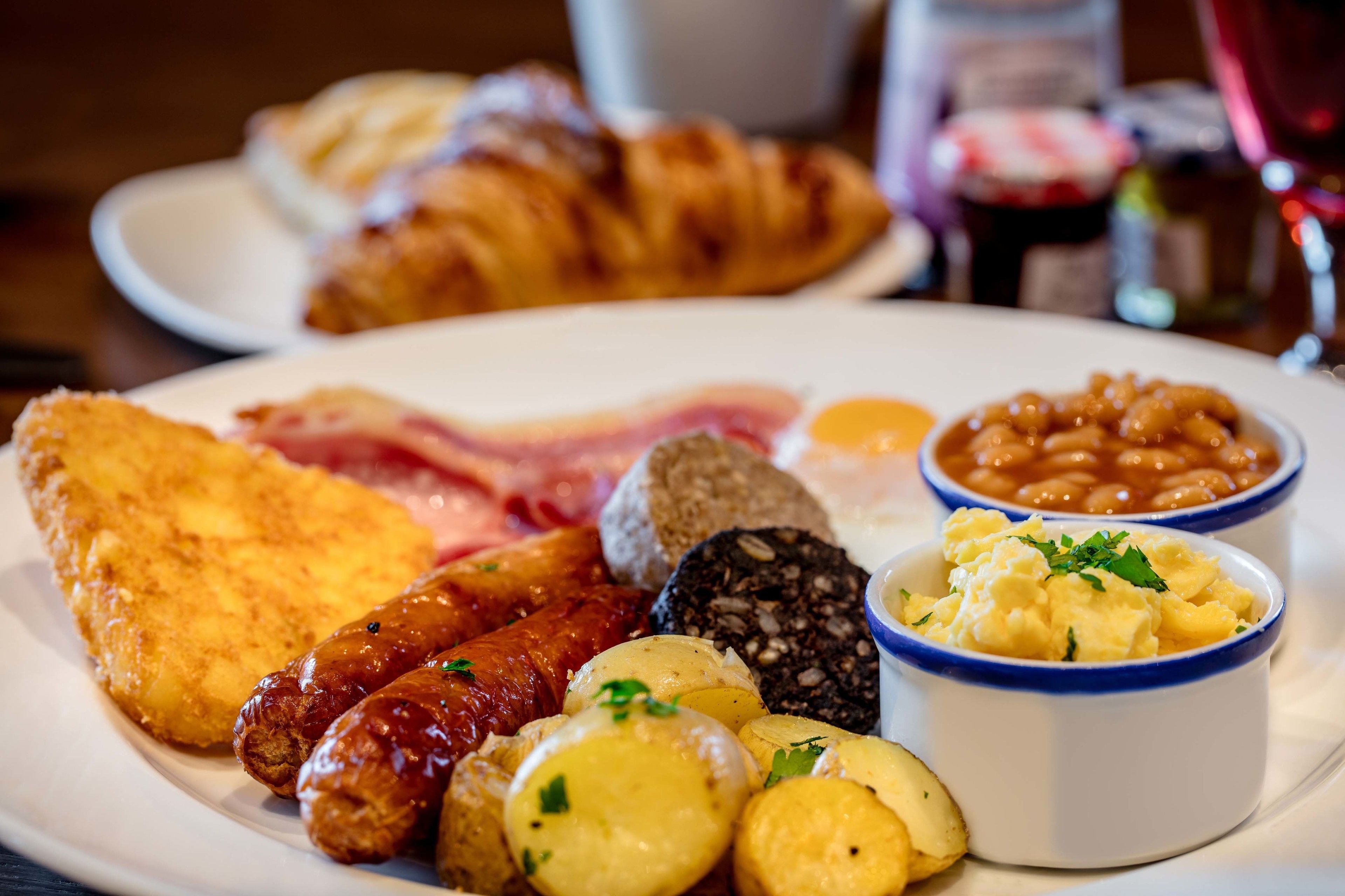 Une assiette de nourriture pour le petit-déjeuner comprenant des saucisses, des œufs, des haricots et des toasts.