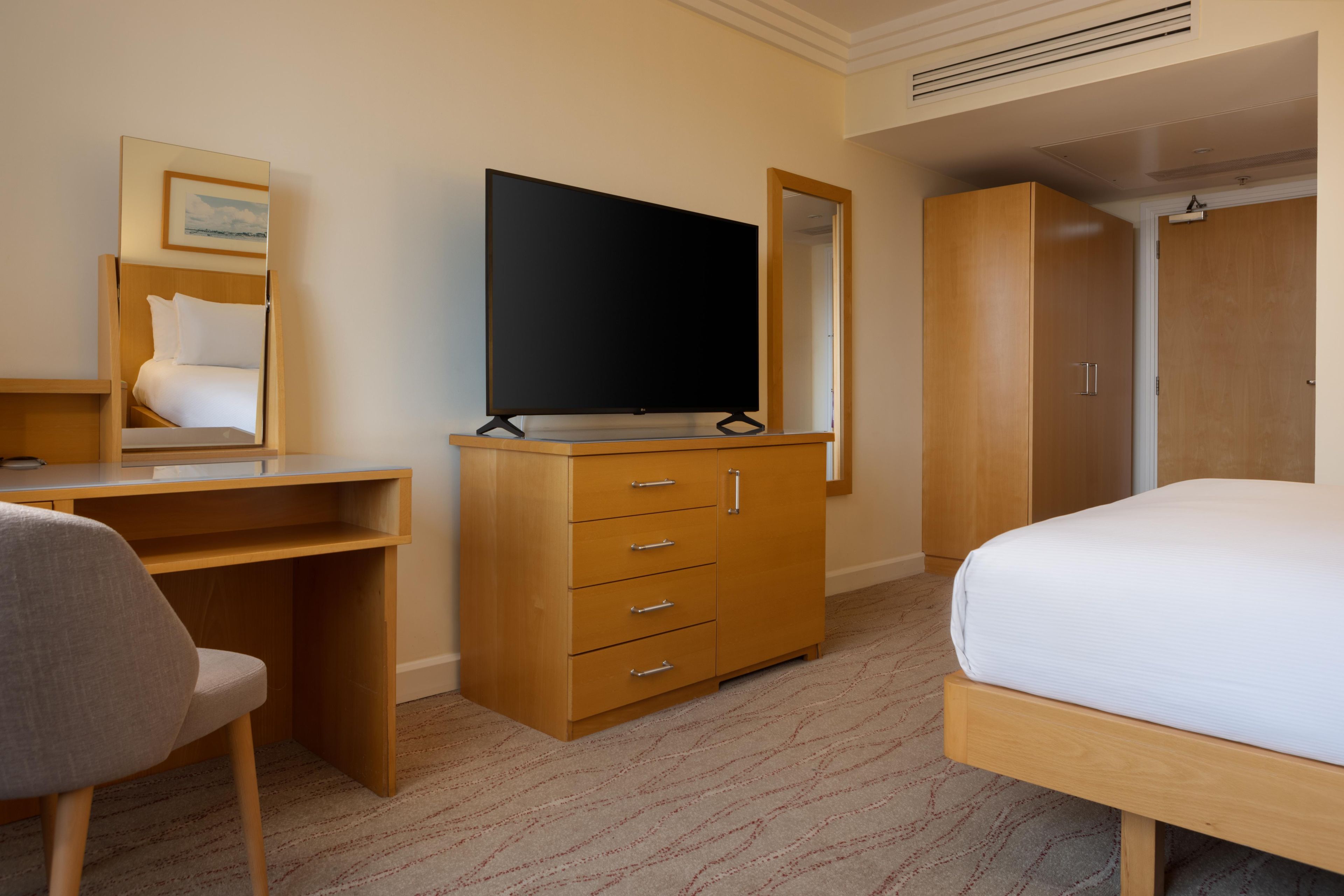 Habitació d'hotel amb un llit, un escriptori, un armari i una televisió.