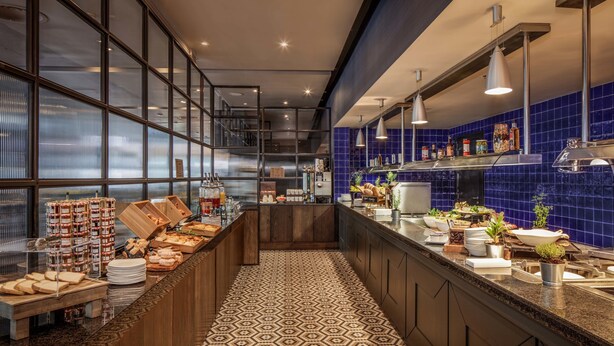 Een moderne keuken met een patroon vloer, een lange toonbank met etenswaren en blauw betegelde muren.