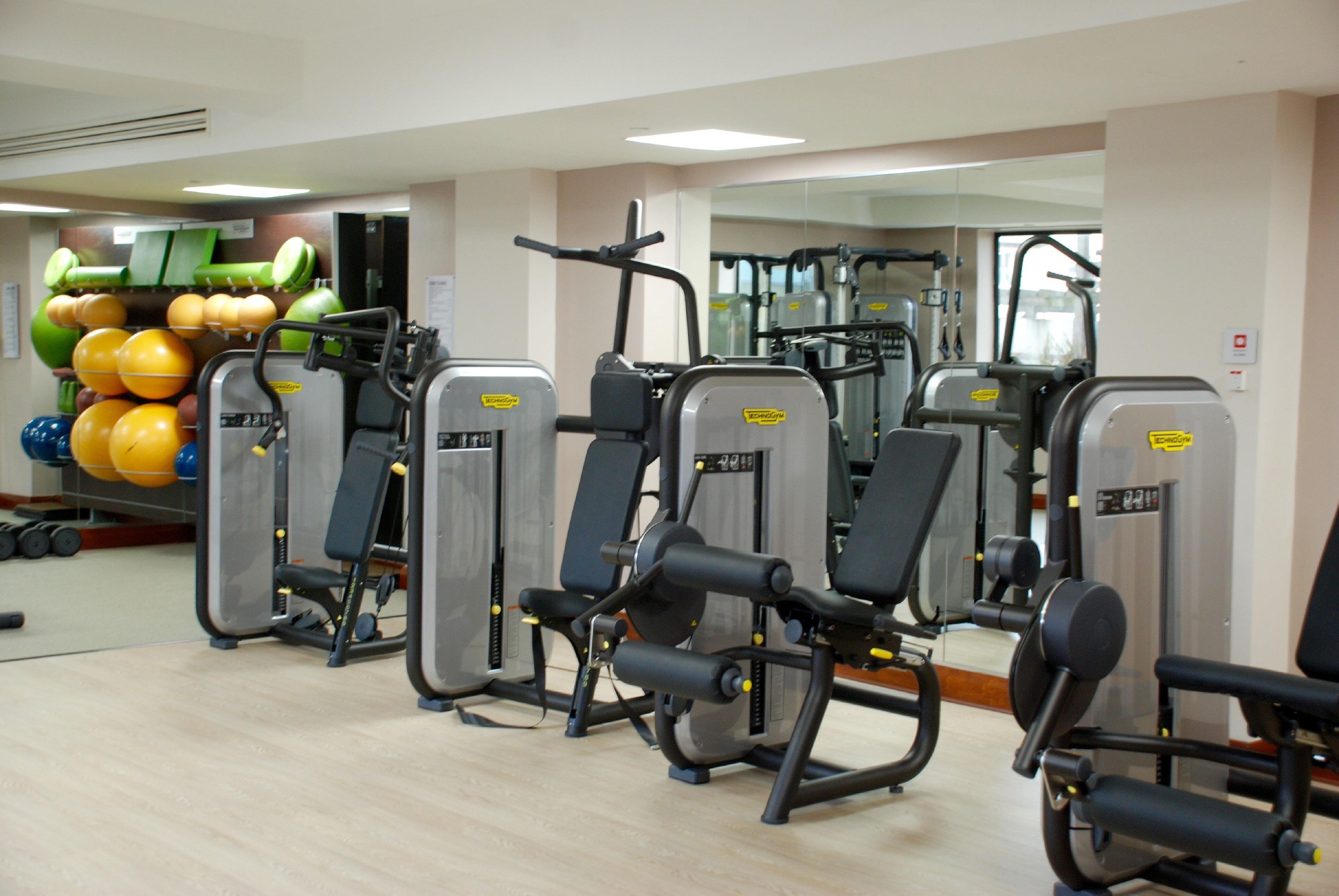 A gym with exercise machines and a wall of exercise balls.