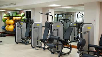 A gym with exercise machines and a wall of exercise balls.