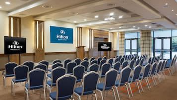 A conference room with rows of chairs, a podium, and a large screen displaying the Hilton Dublin Airport logo.
