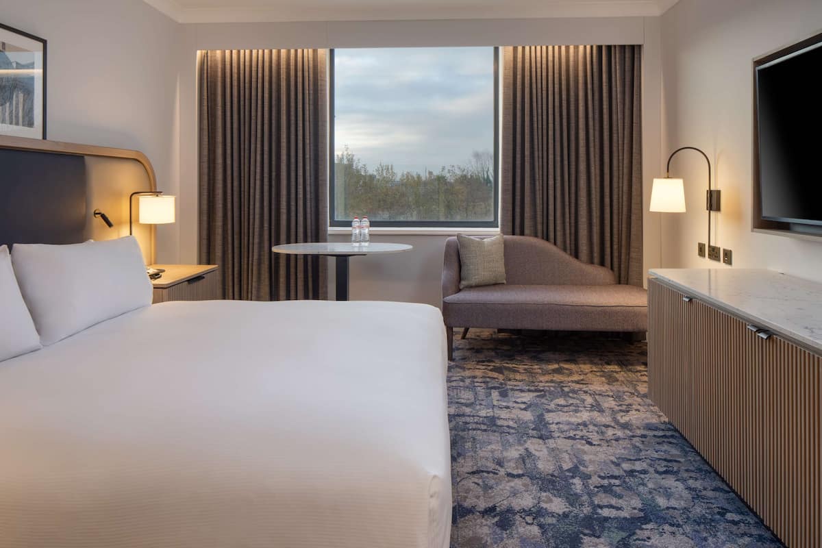 Une chambre d’hôtel avec un grand lit, une petite table, un canapé et un téléviseur.