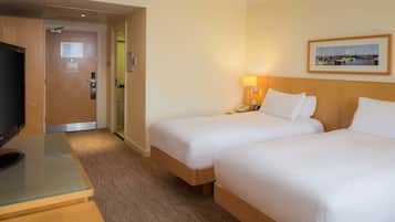 A hotel room with two beds, a TV, a desk, and a framed picture on the wall.
