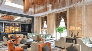 A spacious lobby with modern seating, a bar area, and large windows allowing natural light. - Victoria Grand Hotel (Wenzhou)