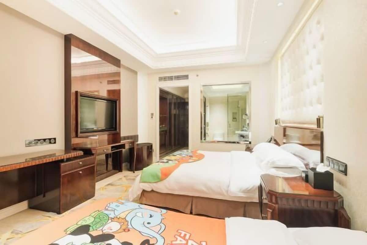Una habitación de hotel con una cama, un escritorio, un televisor y un espejo.