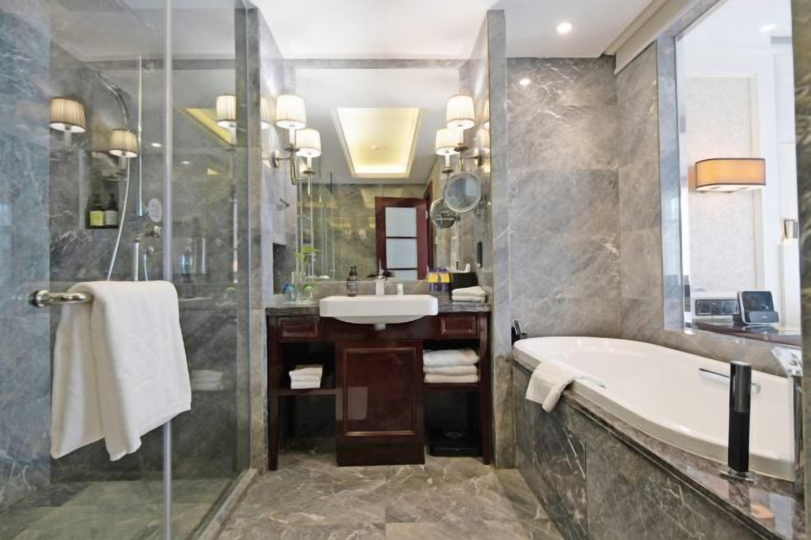 A modern bathroom with a glass-enclosed shower, a freestanding bathtub, and a vanity with a mirror.