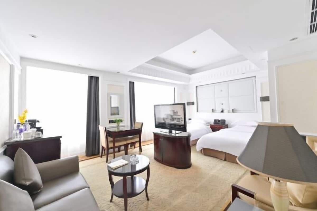Una habitación de hotel con cama, televisor, escritorio, sofá y lámpara.