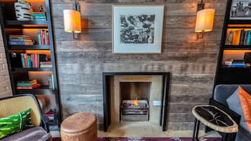 A cozy living room with a fireplace, bookshelves, and a framed picture above the mantel.