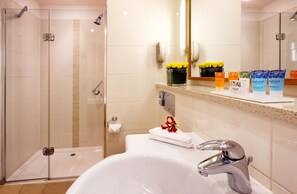 A modern bathroom with a glass-enclosed shower, a white sink with a chrome faucet, and a vanity with toiletries.